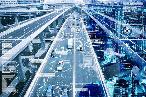 futuristische Stadtansicht Auf dem Bild zu sehen ist eine moderne, futuristisch wirkende Stadtansicht mit mehrspurigen Autobahnen und Verkehrswegen auf verschiedenen Ebenen sowie einer integrierten digitalen Datenvisualisierung, die Verkehrsinformationen darstellt.